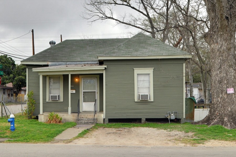 A green wood-frame bungalow on a Houston street